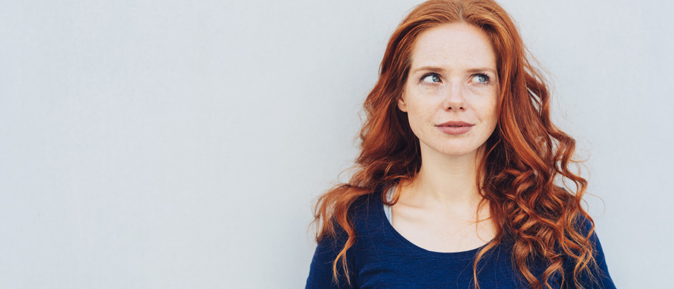 Beautiful red haired woman smiling and looking off in deep thought