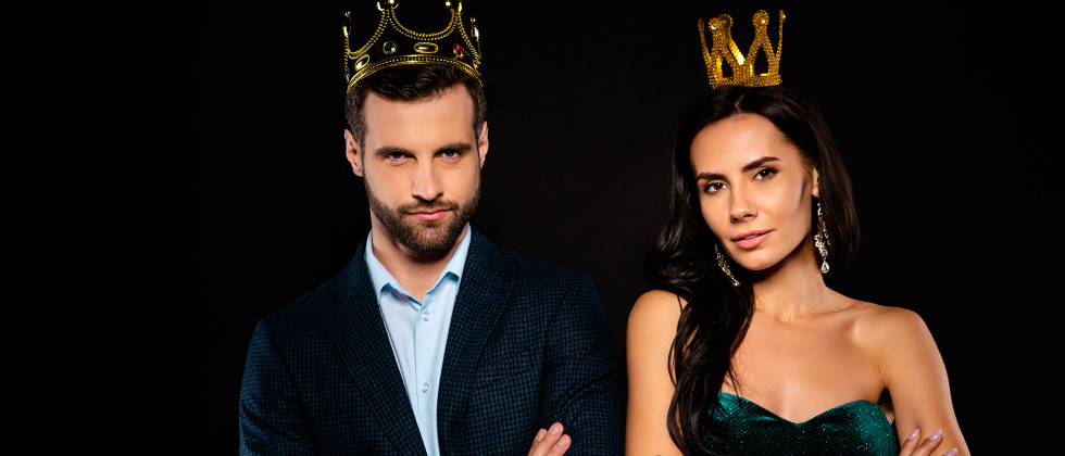 A couple standing dressed up wearing crowns like a king and queen