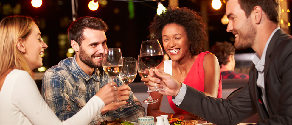Two couples on a double date cheering's with their wine