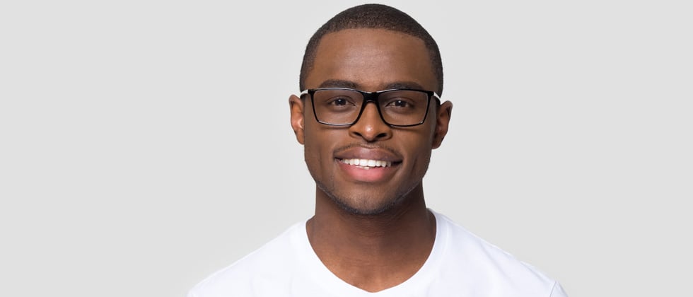 A young man in glasses smiling at the camera