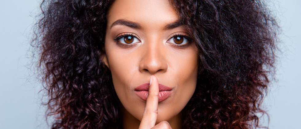 A woman with her finger over her lips as if to say be quiet