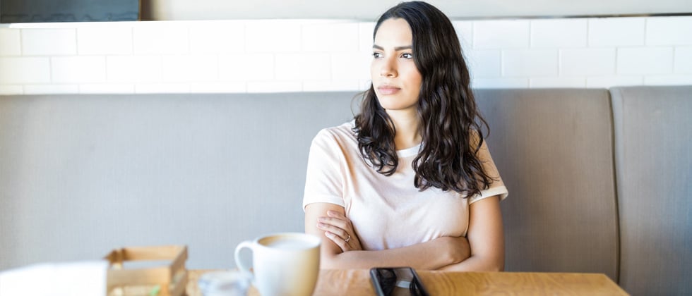 A woman at a café alone looking annoyed and staring into space