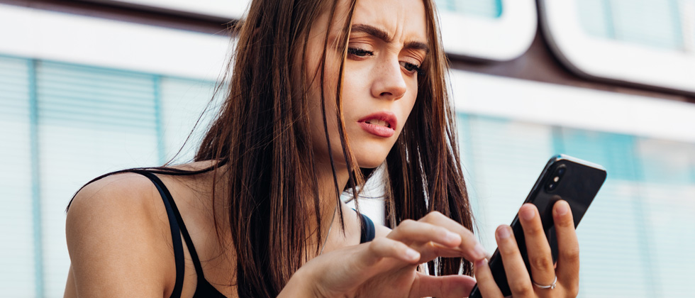 Woman on her phone looking confused by a text message she received