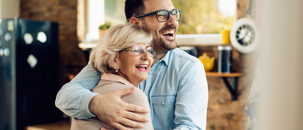 A man and his partner's mom hugging and laughing together
