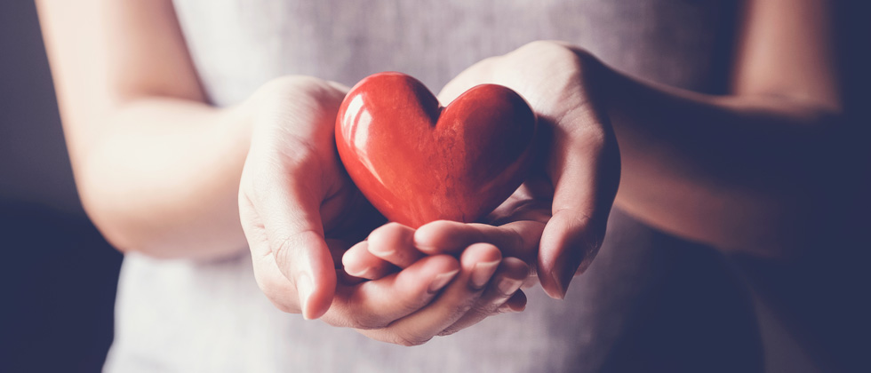 A delicate heart sculpture being cradled in someone's hands