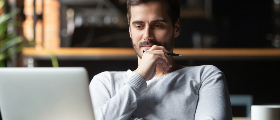 A young man looking at his laptop in deep thought