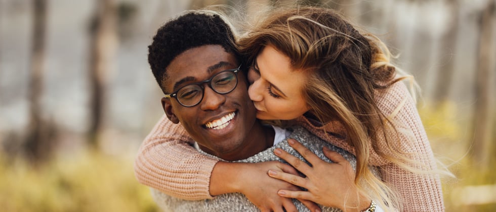 Interracial couple playfully kissing each other and giggling