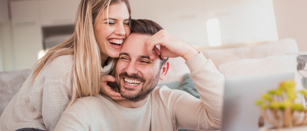 A couple cuddling and laughing with each other on the couch