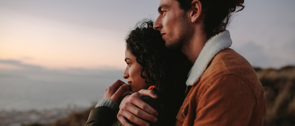 A couple holding each other looking out into the sunset