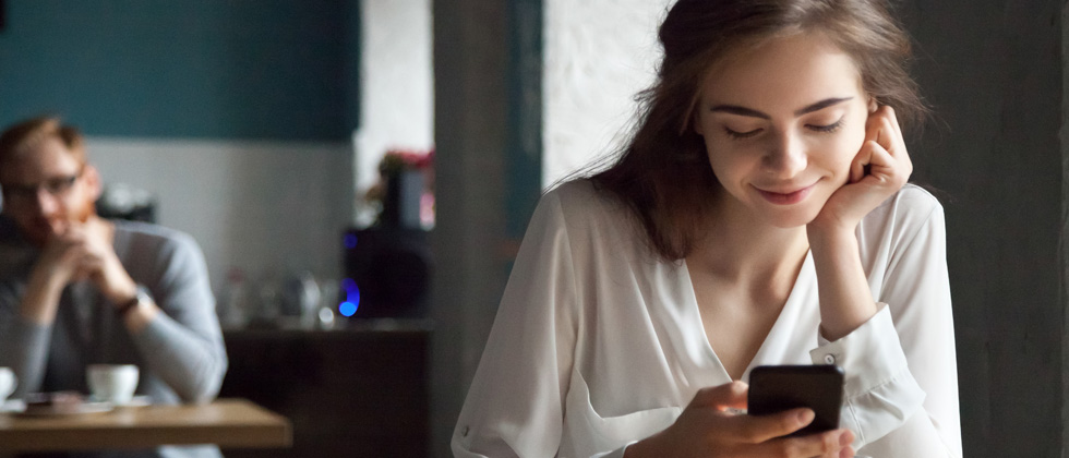 A woman gently smiling while looking down at her phone