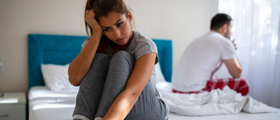 Upset couple sitting on their bed back to back after a fight