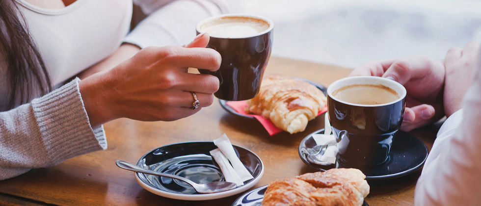 A couple on a coffee date drinking coffee & eating pasteries
