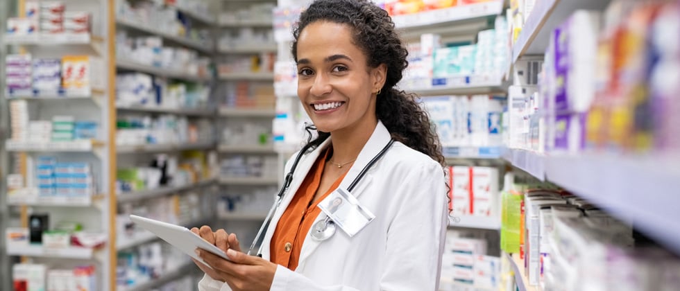 A woman pharmacist standing in a pharmacy looking at a prescription