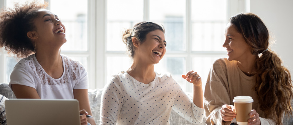 A group of women sitting together and laughing over coffee