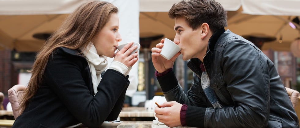 A couple on a date sipping coffee staring at each other