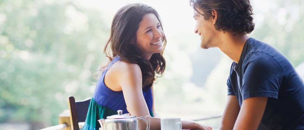 Young couple on a date outside smiling and laughing over coffee