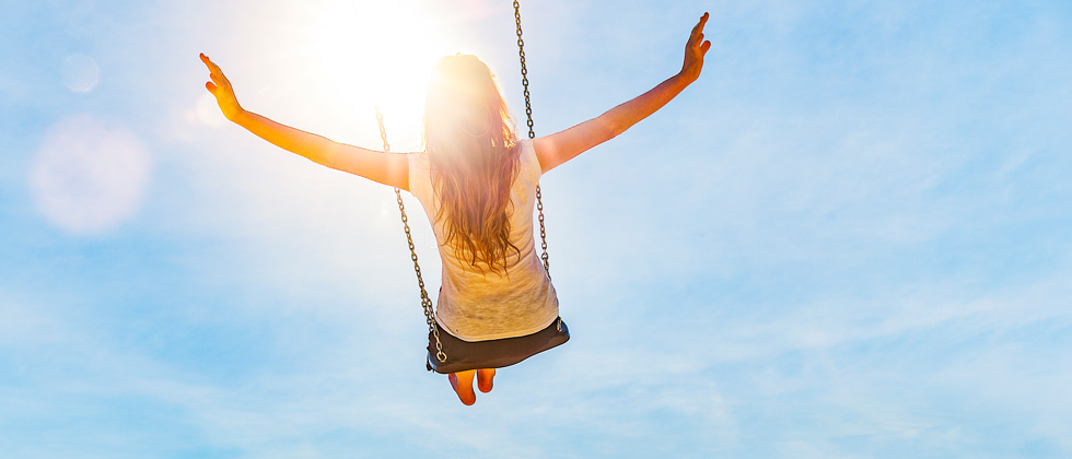 A woman swinging high into the sky with her arms out