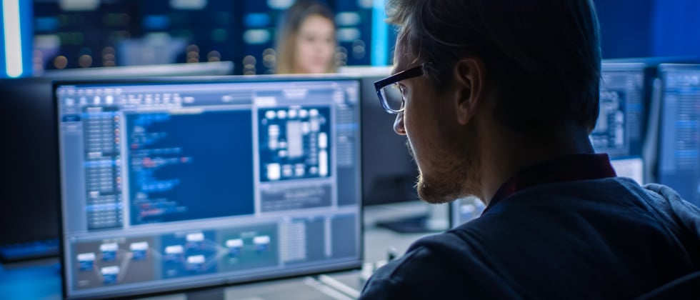 A man intensely working on code at his computer