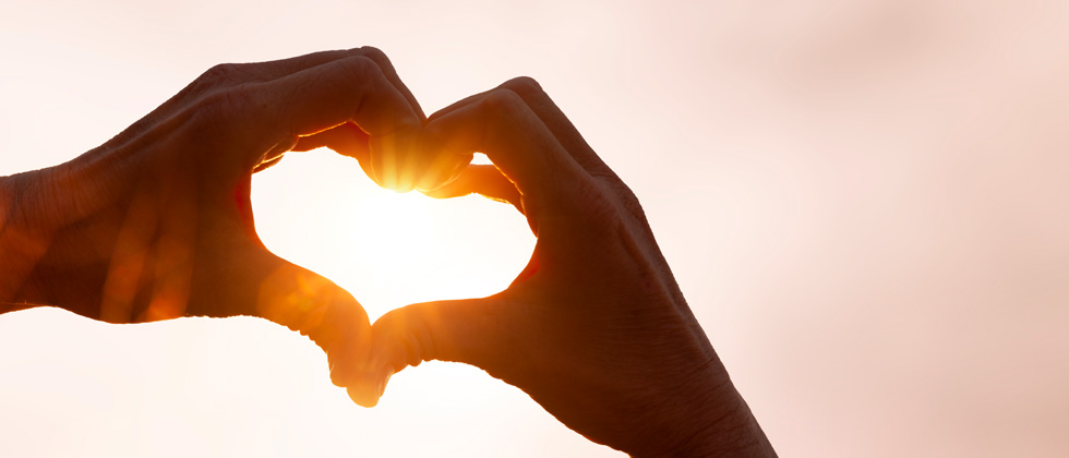 Someone forming a heart in their hands and holding it to the sky
