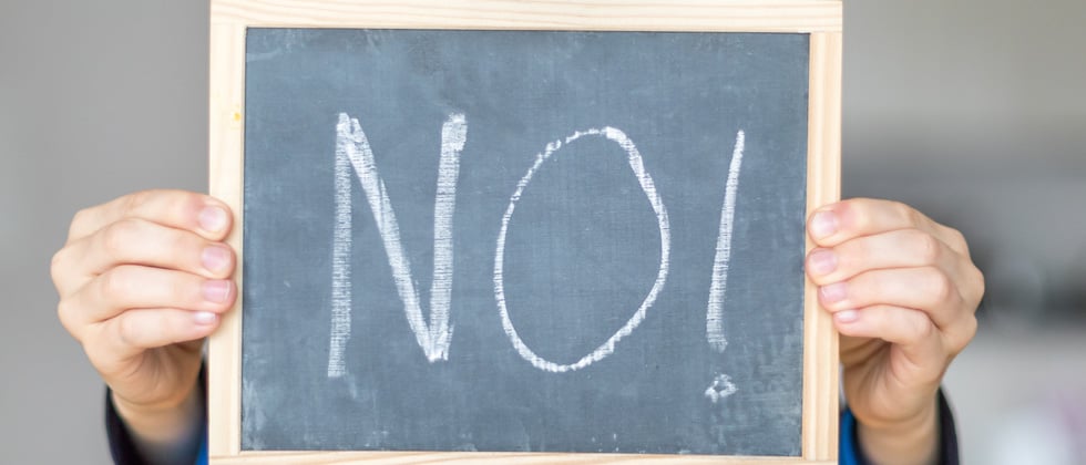 Someone holding up a chalkboard that has NO! written on it