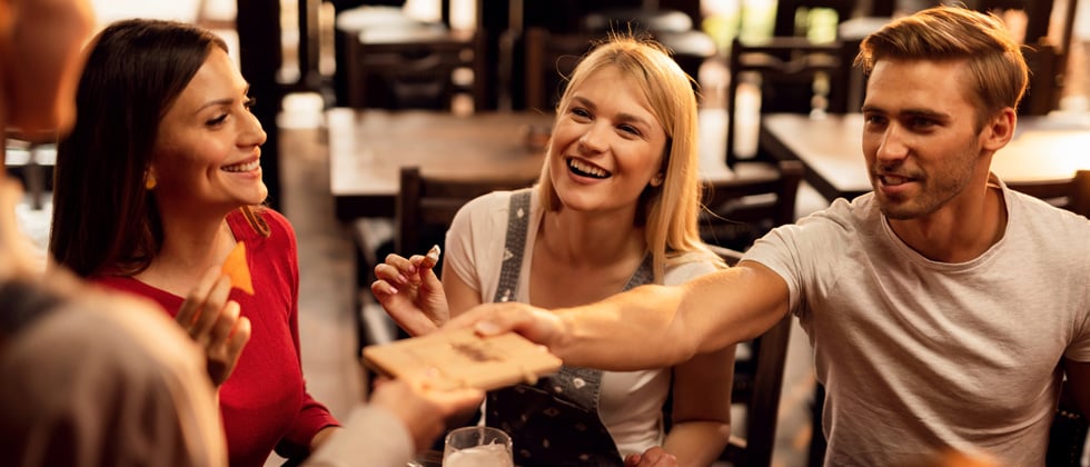 A group of friends at dinner and the guy in the group is paying