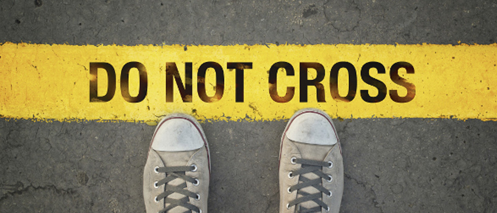Someone standing in front of a yellow line that says do not cross