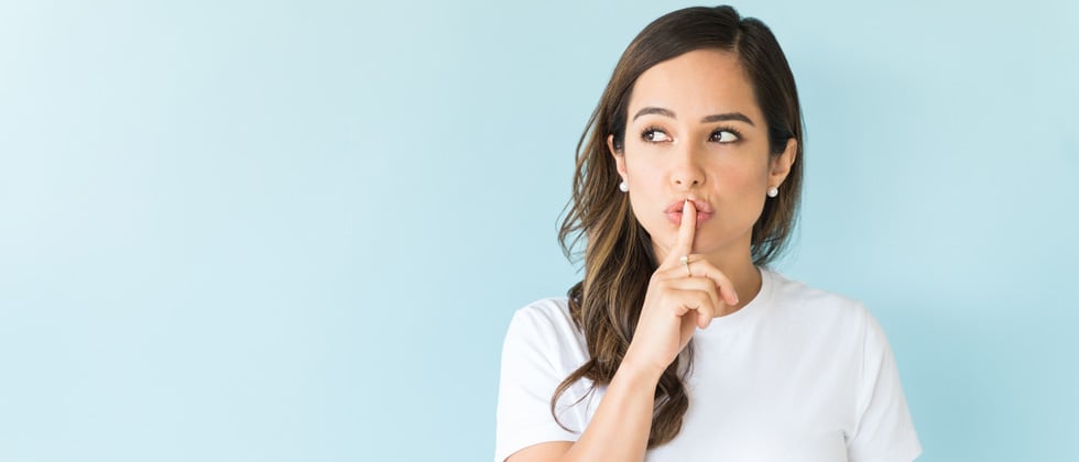 Young woman with her finger over her lips saying shh
