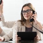 A woman sitting at a desk with 5 arms doing all different things