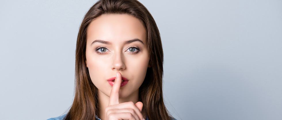 A woman standing with her finger over her lips asking for quiet
