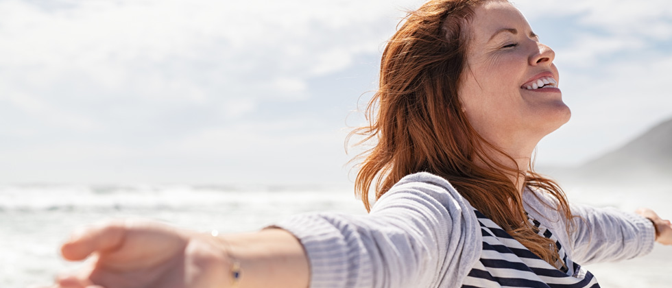 A woman on the beach with her arms open taking in the breeze
