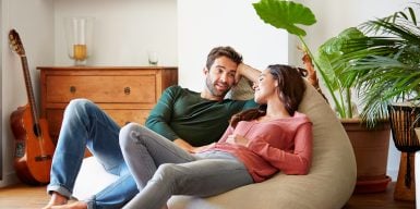 Couple relaxing on a bean bag in the living room talking to each other.