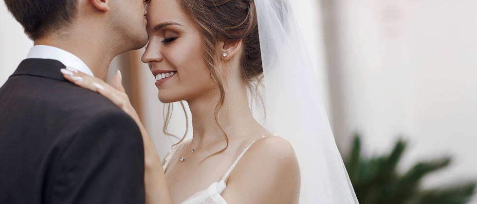 A couple kissing on their wedding day in a bridal gown and tux