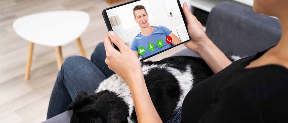 A woman video chatting with a guy while her dog lays on her lap