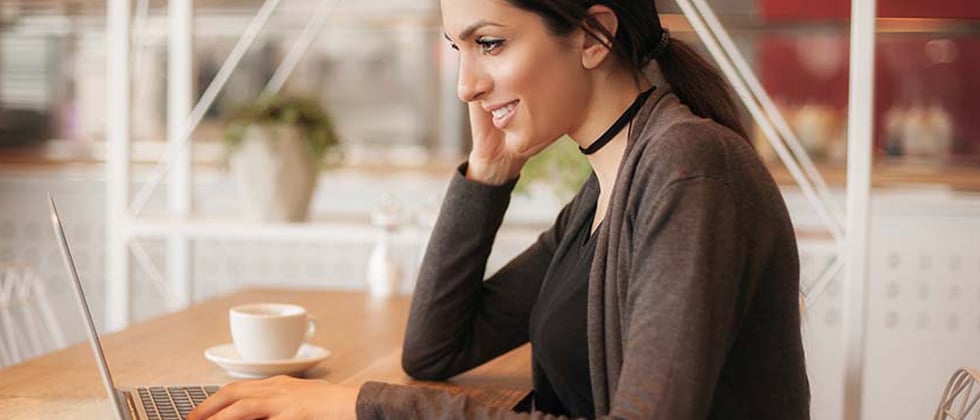 A woman sitting at a cafe working on her laptop