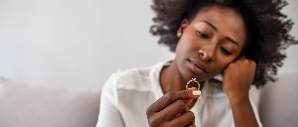 Woman longingly holding her wedding ring deep in thought