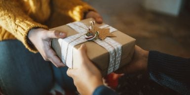 Close-up photography of two hands while giving christmas gift.
