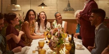 Two married girls having fun at their dinner party with their close friends as they listen to the best mans speech.