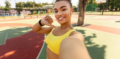 Young motivated woman in a sporty outfit taking a selfie in a park.