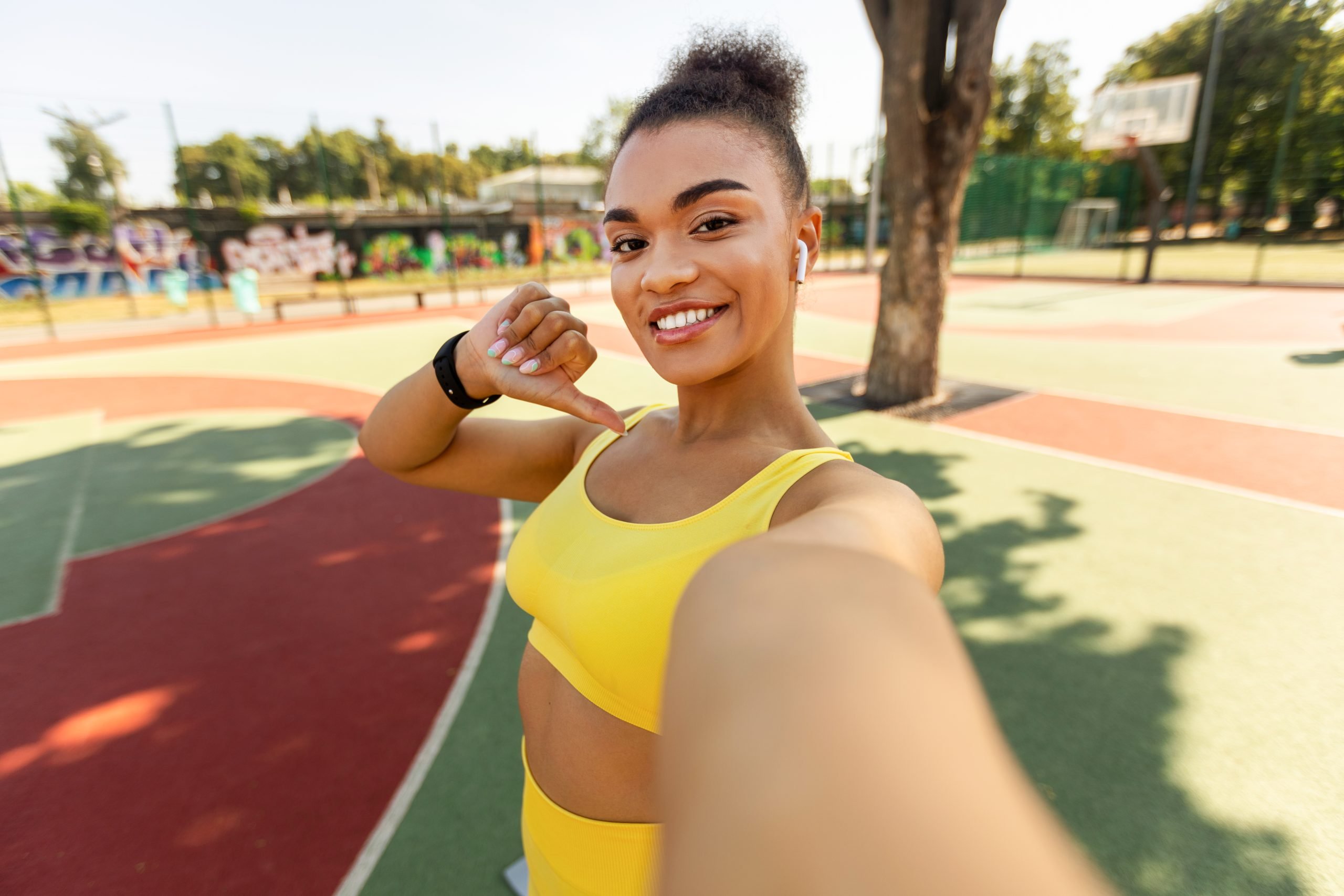 Young motivated woman in a sporty outfit taking a selfie in a park.