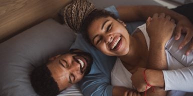 Laughing couple laying in bed.