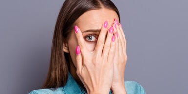 Woman holds hands in front of her face and looks frightened as a symbol of dating anxiety