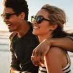 Man and woman laughing together on the beach as a symbol of healthy relationship characteristics