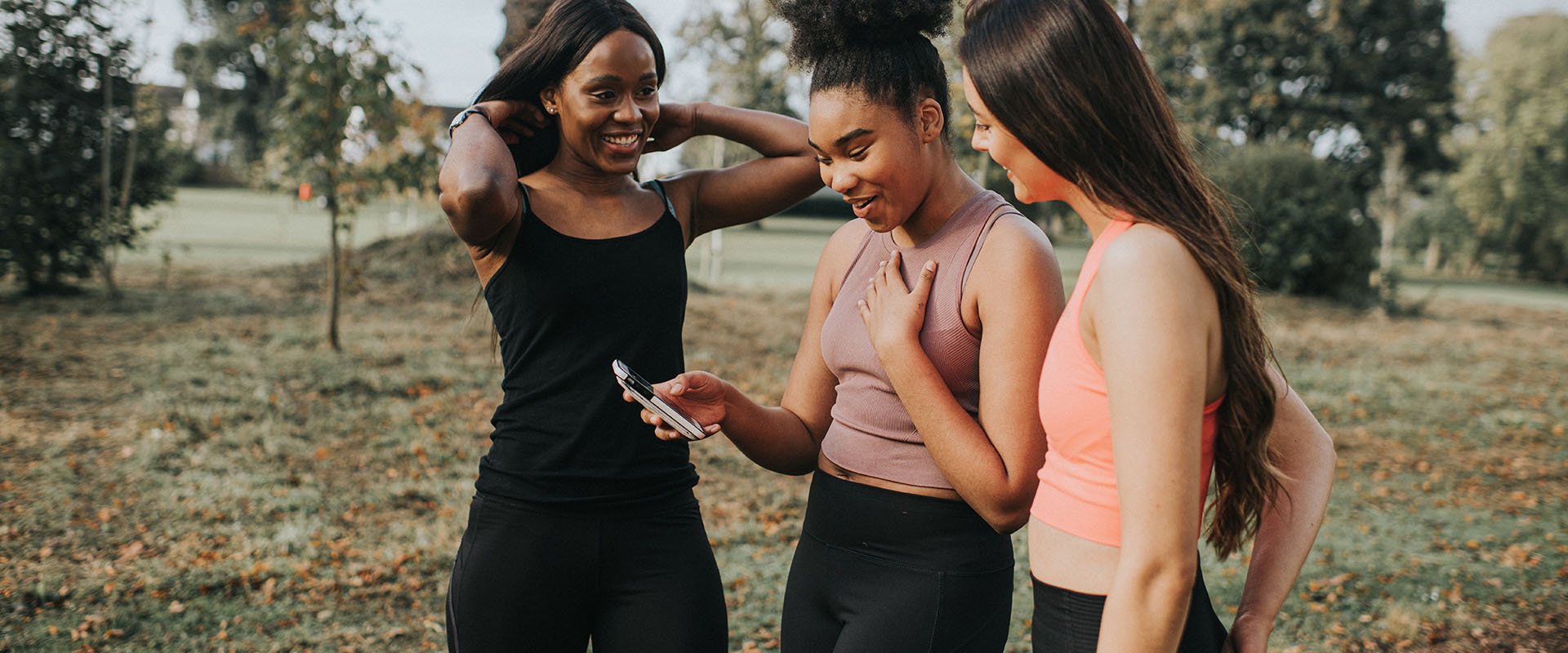 Two women looking together at a cell phone as a symbol for how to successfully start a conversation on a dating app