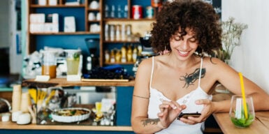 Woman on cell phone in coffee smiles as a symbol for meeting people online