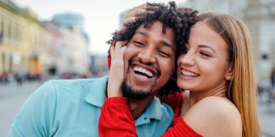 Woman holding man's face in her hands and both laughing as a symbol for singles who have never been in a relationship before