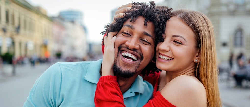 Woman holding man's face in her hands and both laughing as a symbol for singles who have never been in a relationship before