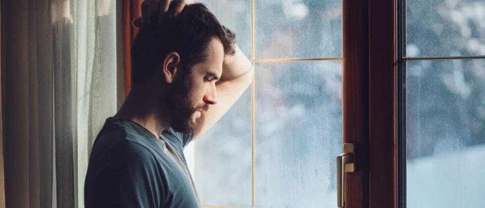 Man leans against the window and looks thoughtful as an example of when you make plans but don't write them back