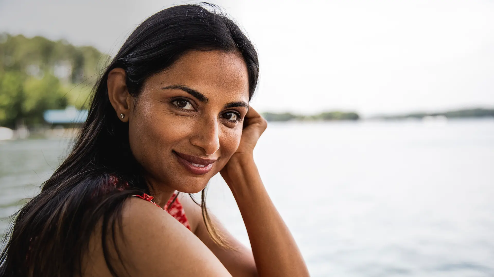 A indian woman is sitting next to a lake.