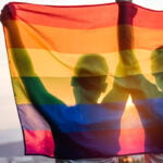 Two people hold up the lgbtq flag