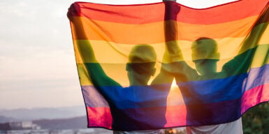 Two people hold up the lgbtq flag